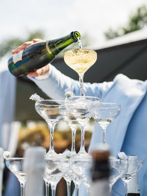 Elegant champagne tower being filled at an outdoor wedding celebration in Brazil.